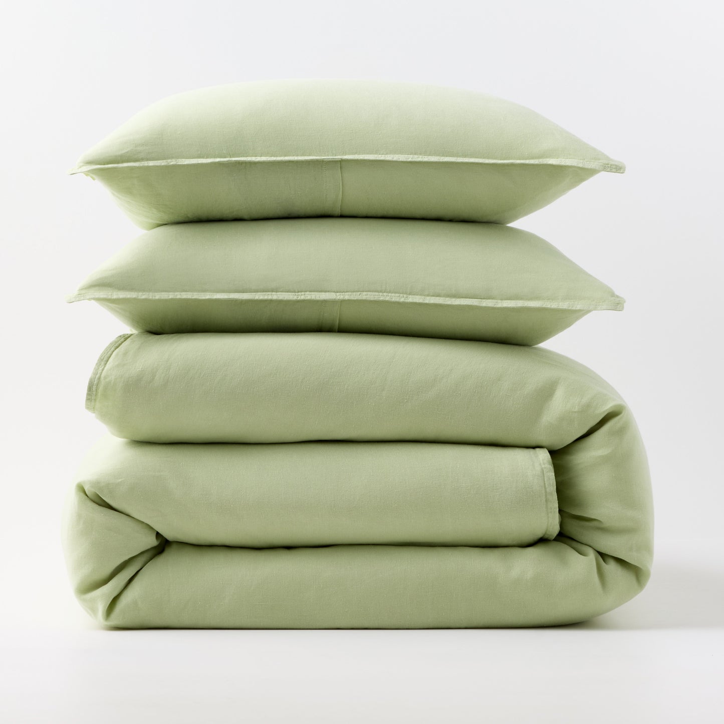 Stacked mint green European washed linen duvet cover and two matching pillow shams on a white background.