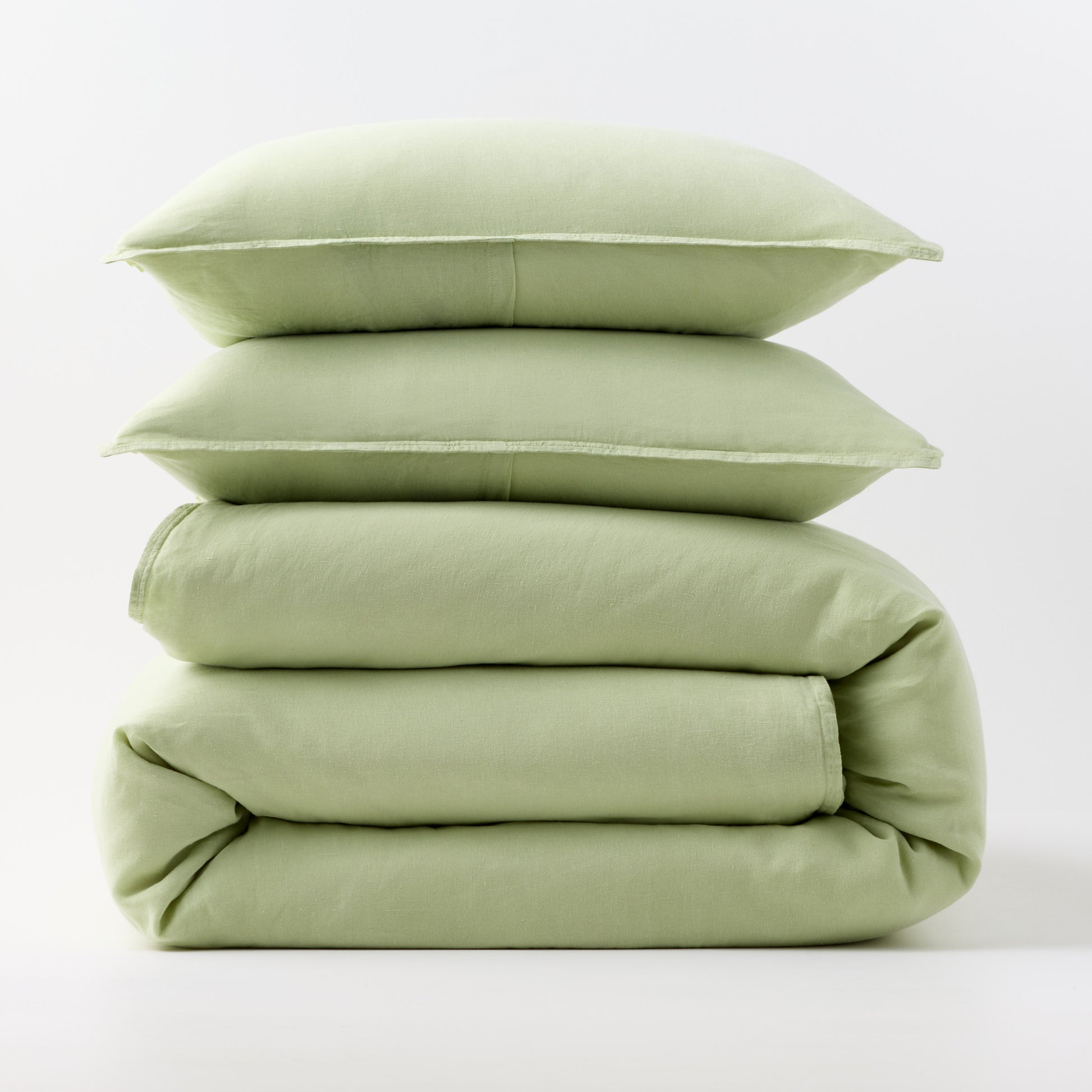 Stacked mint green European washed linen duvet cover and two matching pillow shams on a white background.