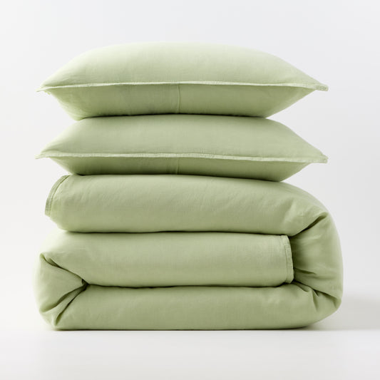 Stacked mint green European washed linen duvet cover and two matching pillow shams on a white background.