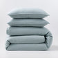 Stacked mist blue European washed linen duvet and two matching pillow shams on a white background.