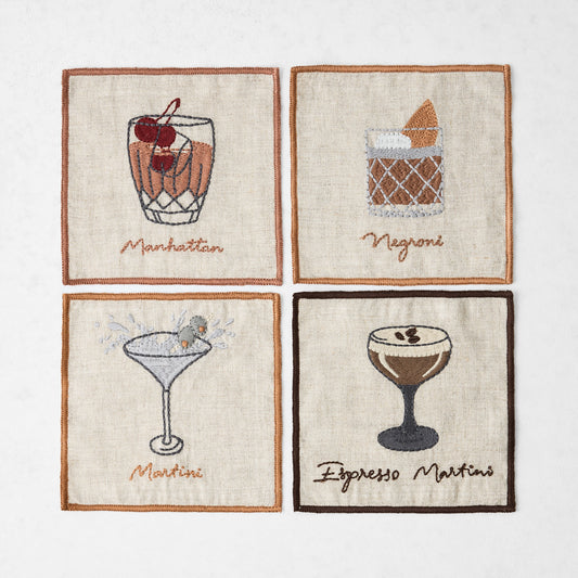 Set of four 5.5-inch square natural linen coasters featuring embroidered Manhattan, Negroni, Martini, and Espresso Martini.