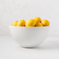 White ceramic serve bowl filled with bright yellow lemons.