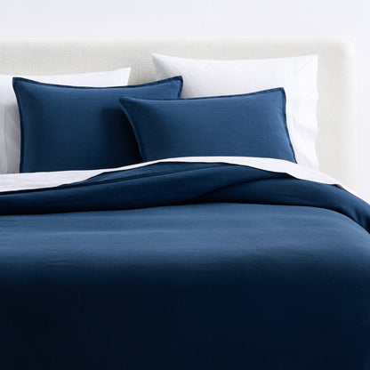 Moonlight blue European washed linen duvet cover and matching shams on a bed with white pillows.