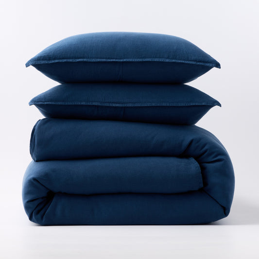 Stacked moonlight blue European washed linen duvet and two matching pillow shams on a white background.
