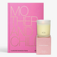 Pink "Mother And Child" book with gold text, beside a lit Savannah candle in a frosted glass holder and pink box.