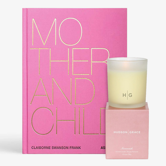 Pink "Mother And Child" book with gold text, beside a lit Savannah candle in a frosted glass holder and pink box.
