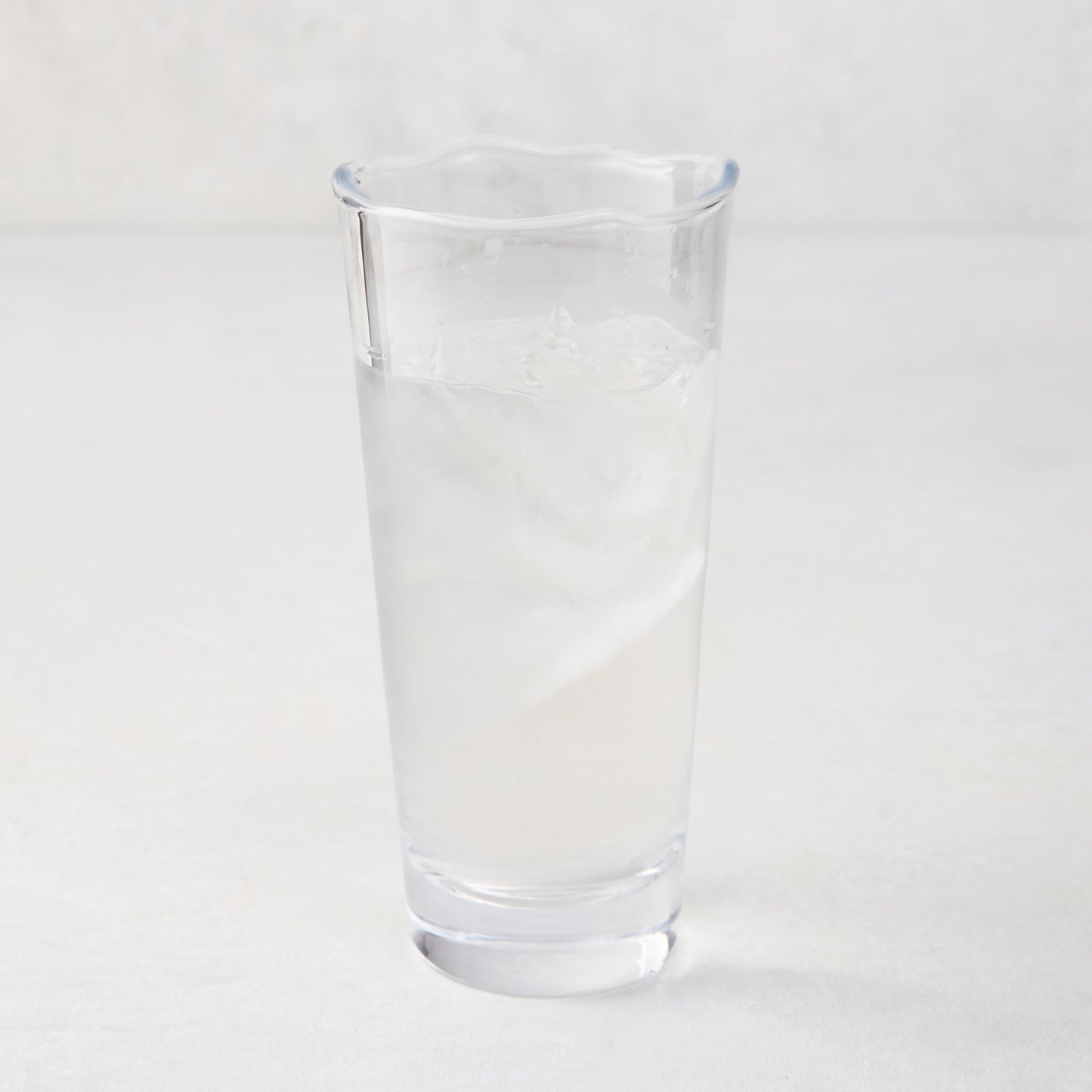 Mozes Scissor-Cut Water Glass, clear air-blown glass, 10.5 oz, with a rippled rim, filled with ice water.