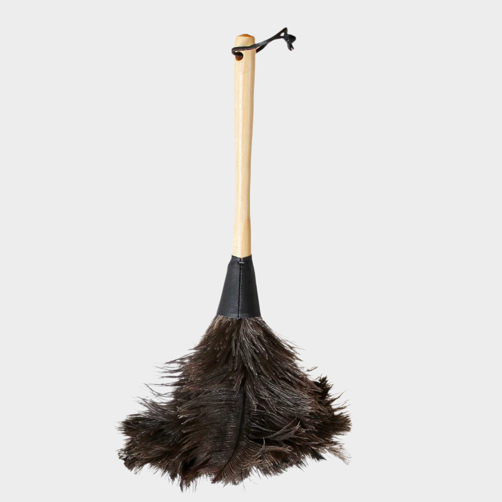 Natural feather duster with dark brown feathers, blond wood handle, black leather ferrule and hanging strap.