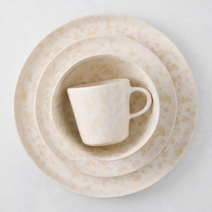 Natural Nuno Splatter stoneware dinner plate, salad plate, bowl, and mug with beige spots on cream.