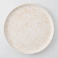 Natural Nuno Splatter 11" stoneware dinner plate with beige spots on a pale cream base.