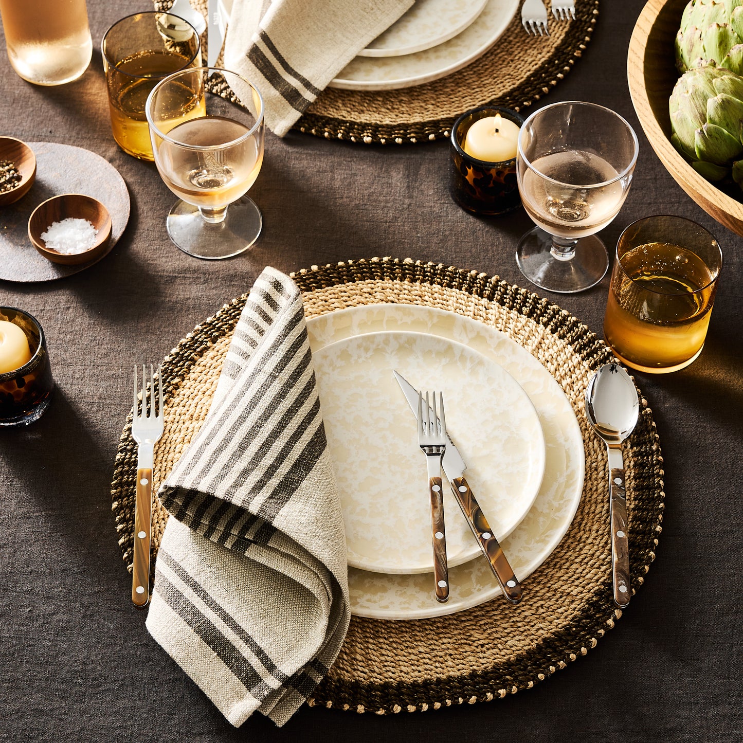 Natural Nuno Splatter stoneware salad plate with unique beige spots on a pale cream base, set on a woven placemat.