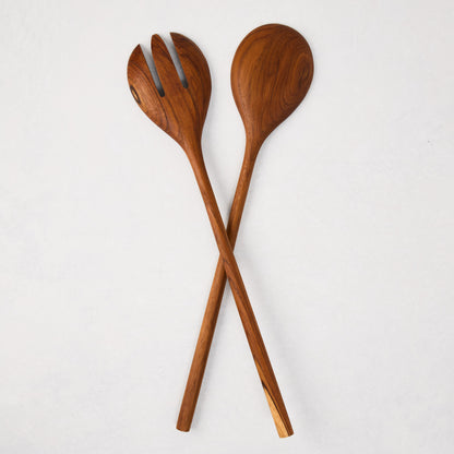 Natural teak wood long-handled 2-piece serving set, spoon and fork, crossed on white.