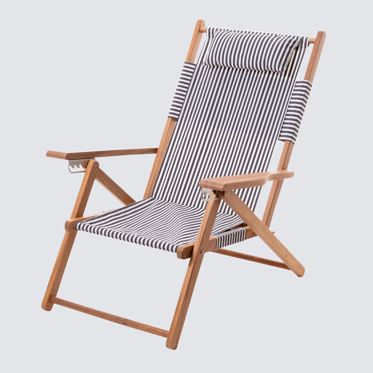 Navy and white stripe canvas reclining beach chair with a teak wood frame and padded headrest.