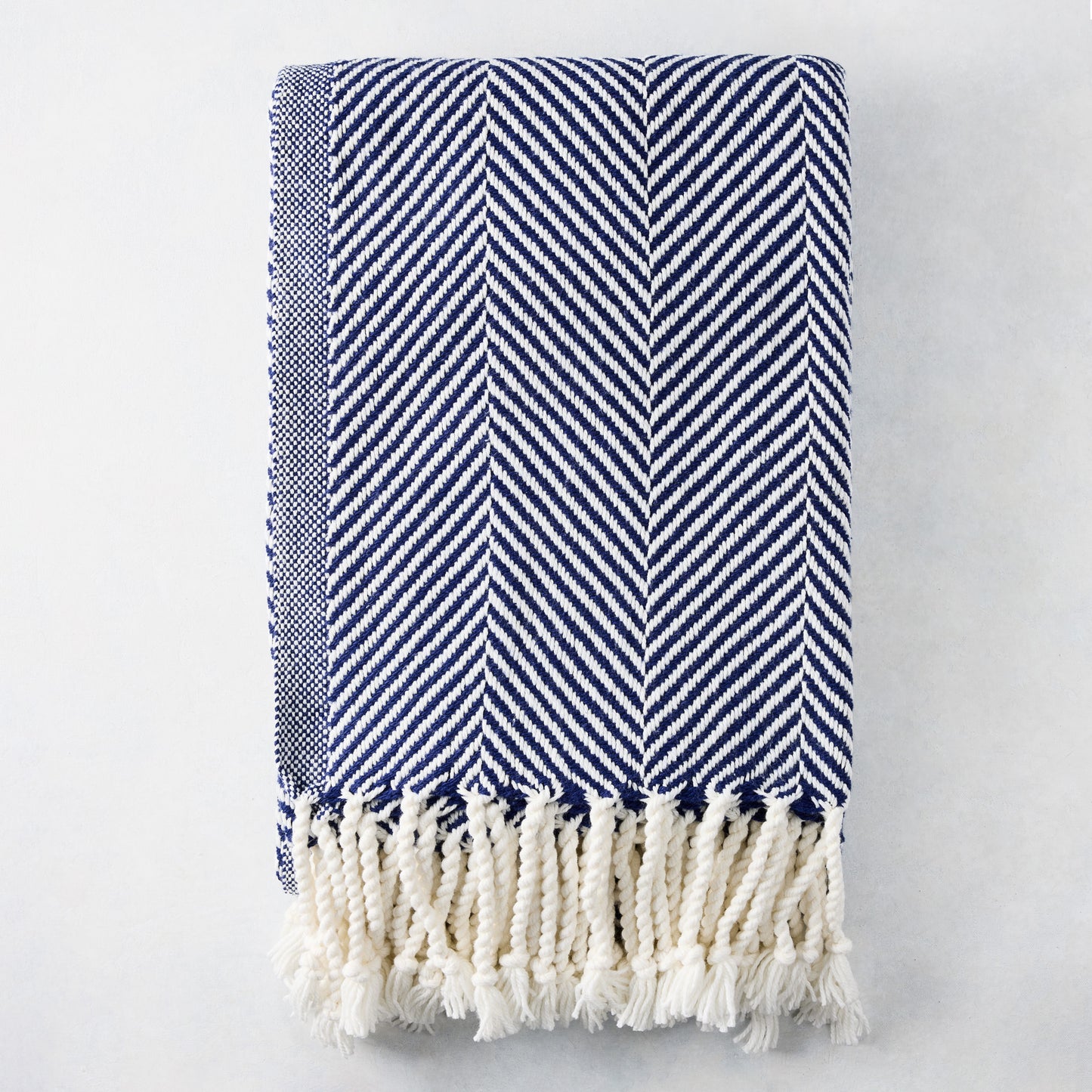 Navy blue and white chevron cotton throw blanket with thick rope fringe.