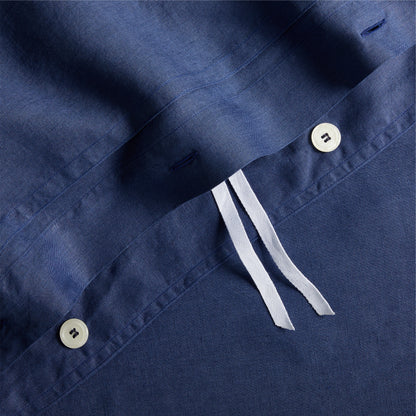 Navy blue washed linen duvet cover with white buttons, double-needle stitching, and white corner ties.