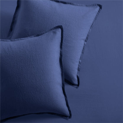 Two navy blue washed linen pillow shams with 2" flange and double-needle stitching.