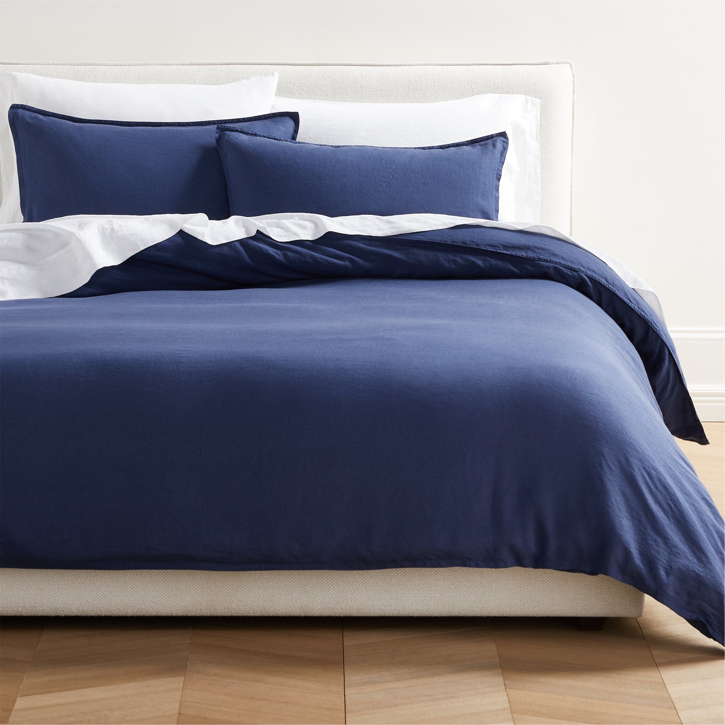 Navy blue washed linen pillow shams and duvet cover on a bed with white sheets.
