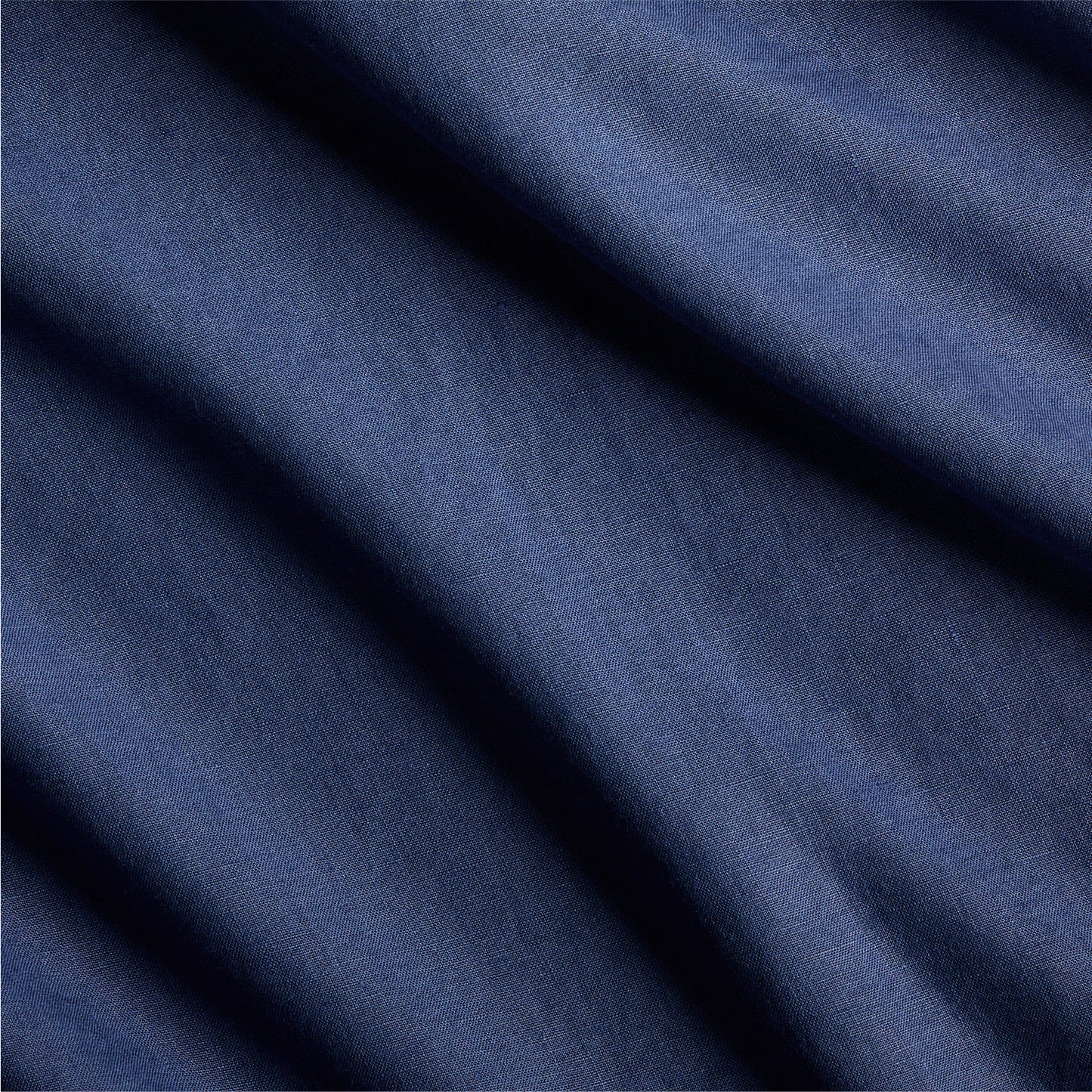 Close-up of navy blue washed linen fabric with subtle texture and soft folds.