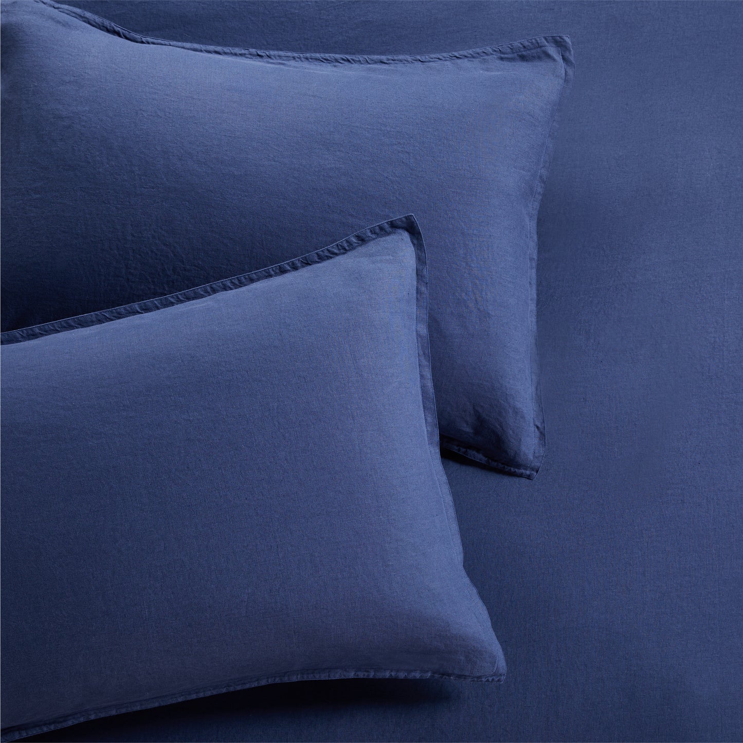 Set of two navy blue washed linen pillow shams with 2" flange and double-needle stitching.
