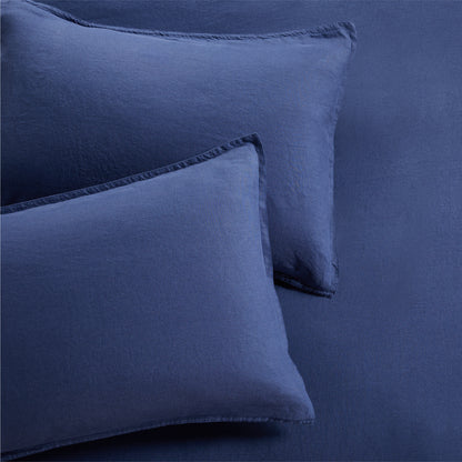 Set of two navy blue washed linen pillow shams with 2" flange and double-needle stitching.
