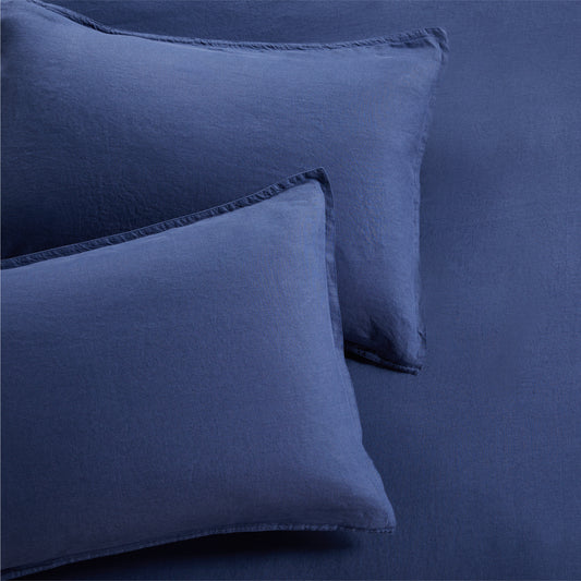 Set of two navy blue washed linen pillow shams with 2" flange and double-needle stitching.