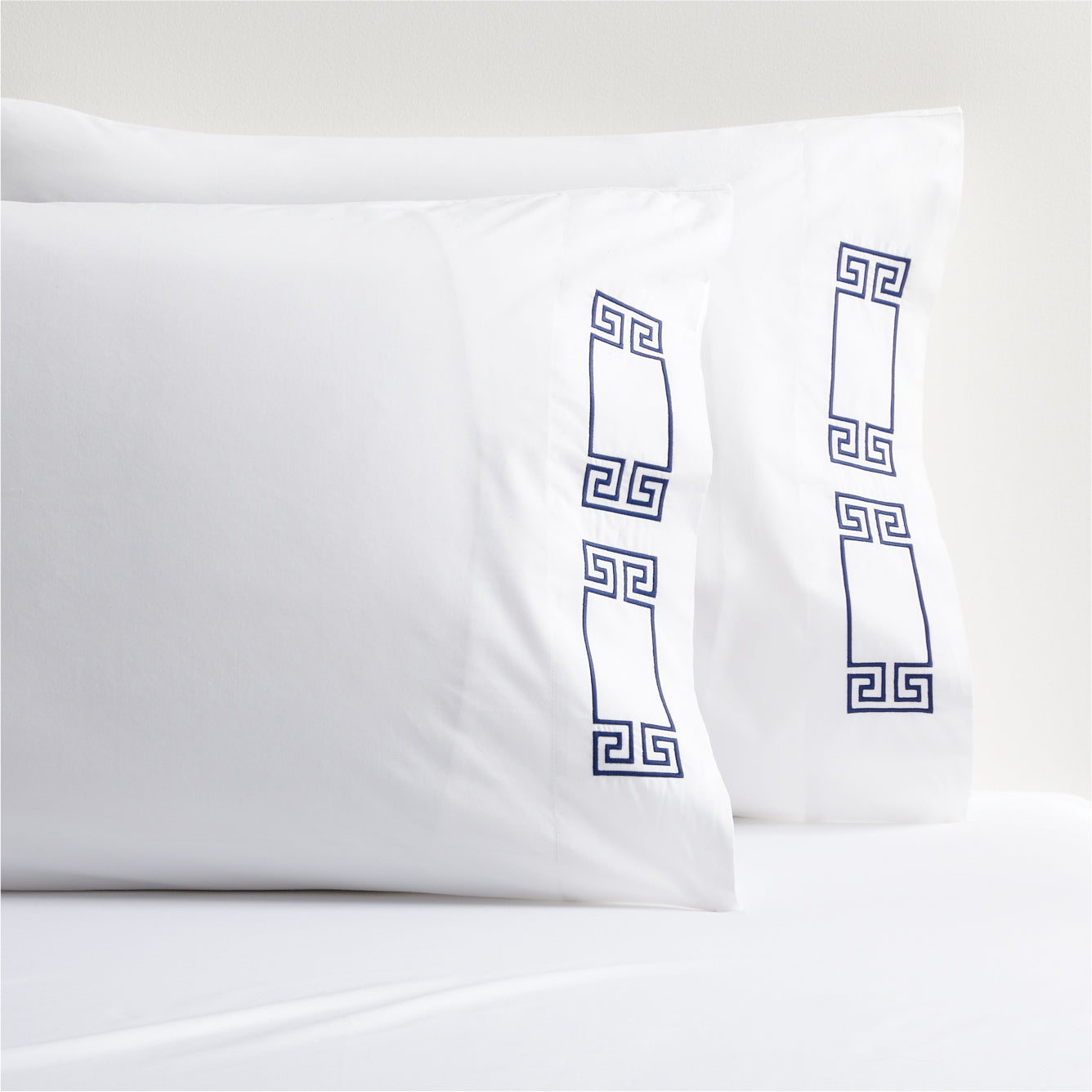 White percale pillowcases with navy embroidered Greek key motif.
