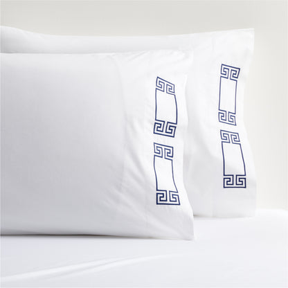 White percale pillowcases with navy embroidered Greek key motif.