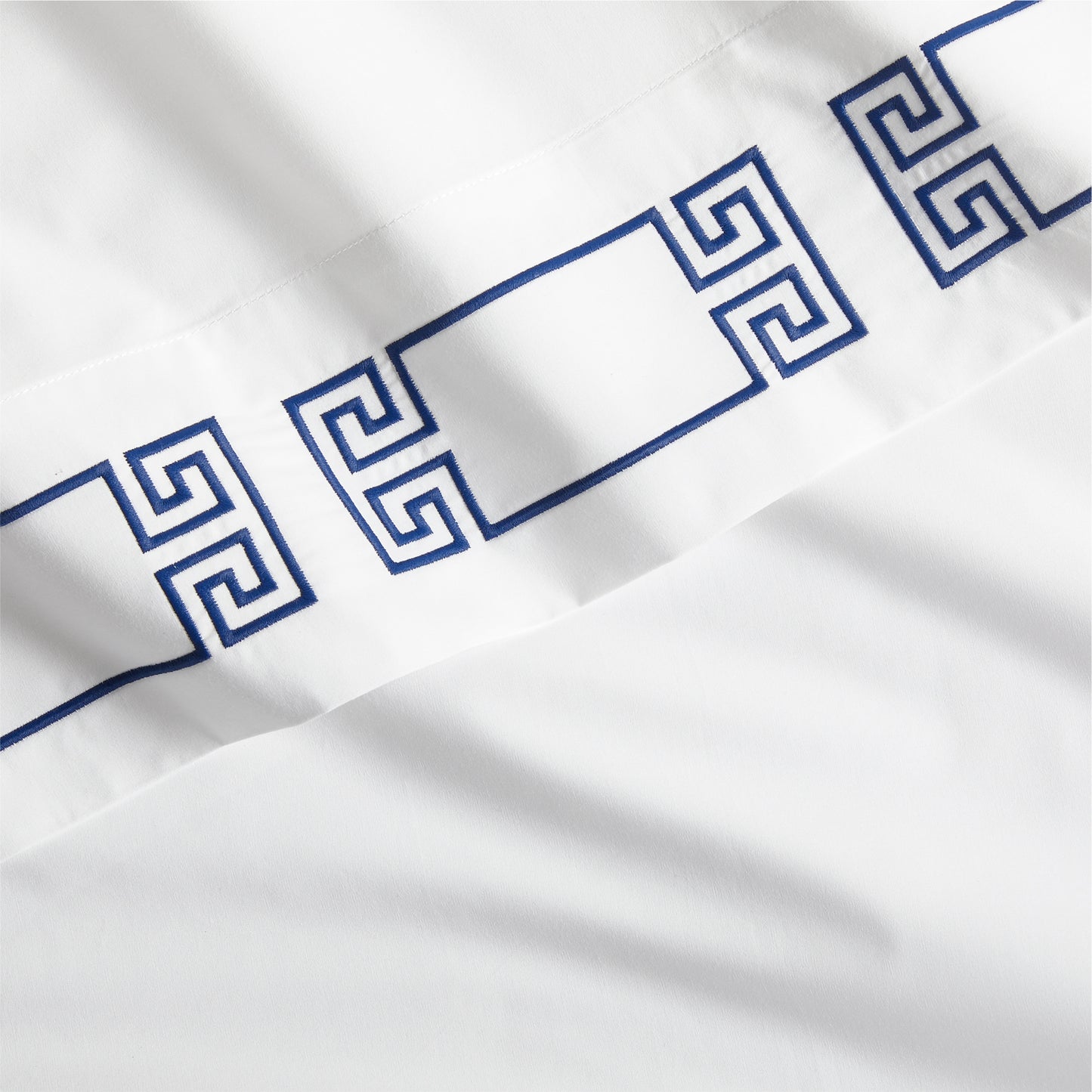 White percale sheet with navy embroidered Greek key border.