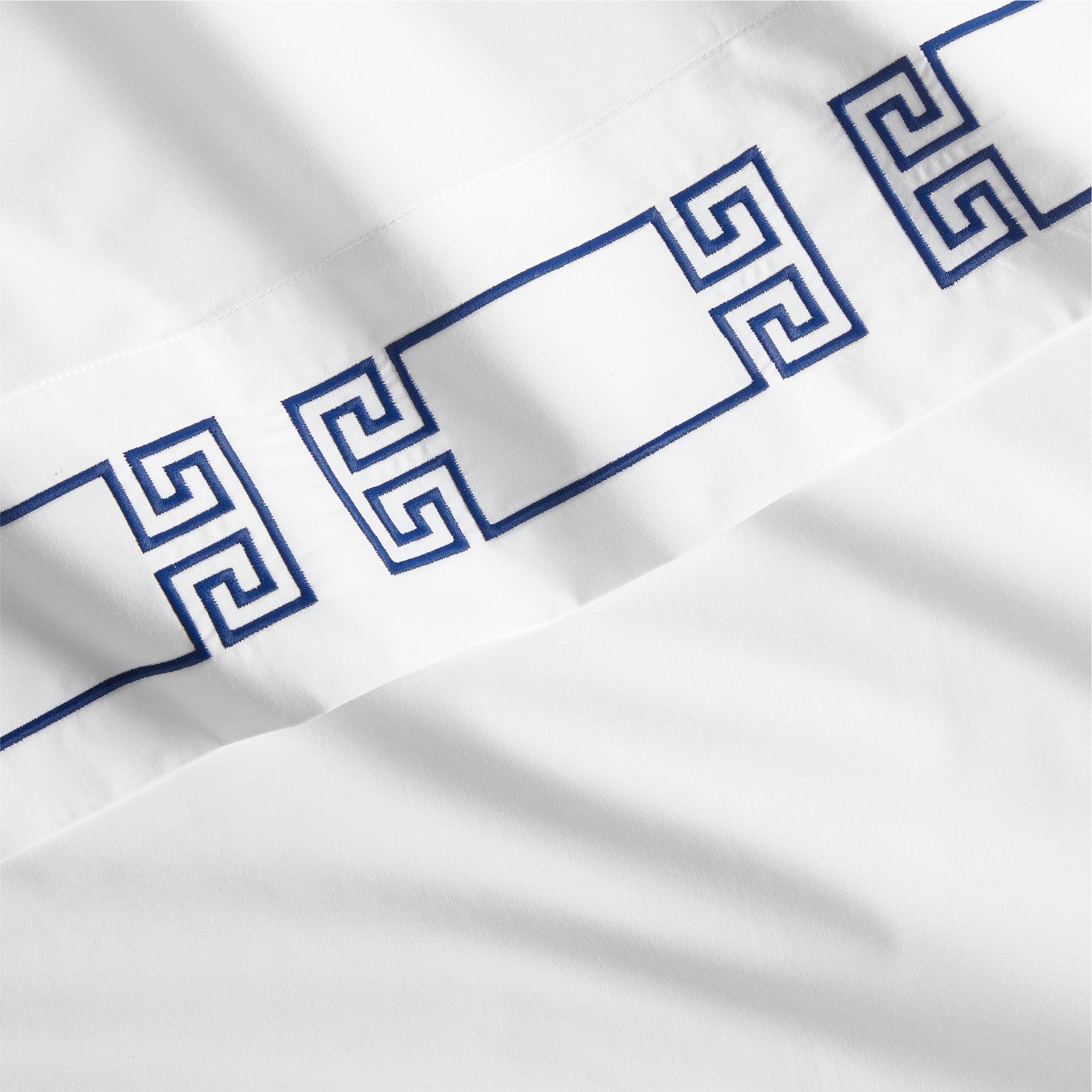 White percale sheet with navy embroidered Greek key border.