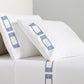 White percale sheet set with navy embroidered Greek key motif on pillowcases and flat sheet.