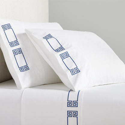 White percale sheet set with navy embroidered Greek key motif on pillowcases and flat sheet.
