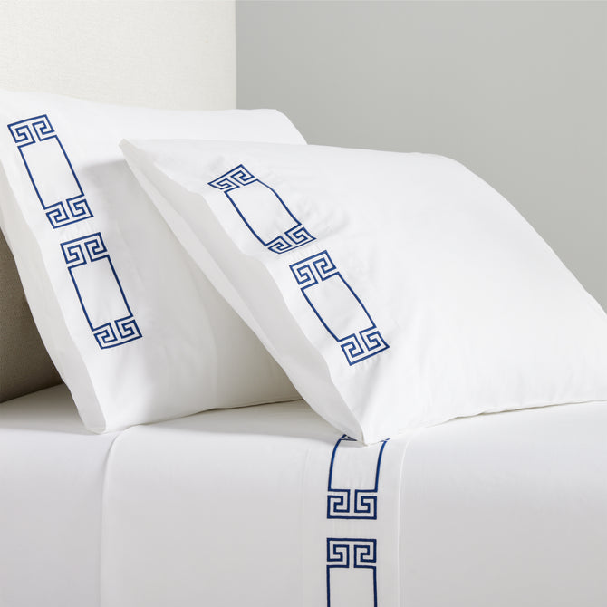 White percale sheet set with navy embroidered Greek key motif on pillowcases and flat sheet.