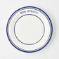 Navy blue and white ceramic salad plate with "Bon Appetit" text and double navy blue rim.