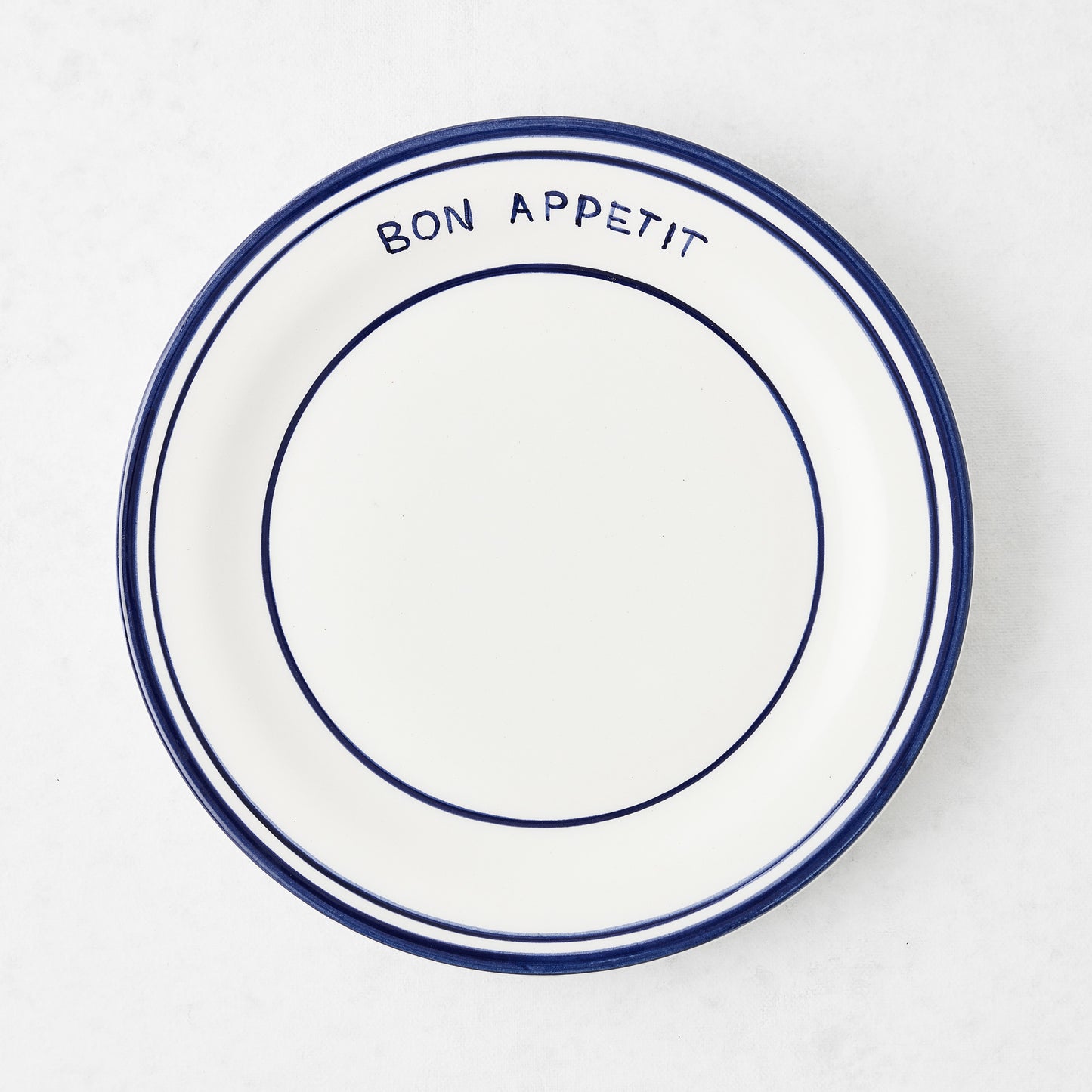 Navy blue and white ceramic salad plate with "Bon Appetit" text and double navy blue rim.