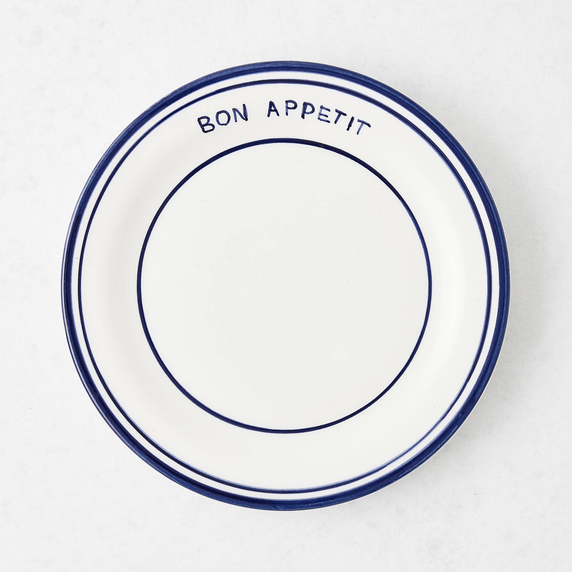 Navy blue and white ceramic salad plate with "Bon Appetit" text and double navy blue rim.