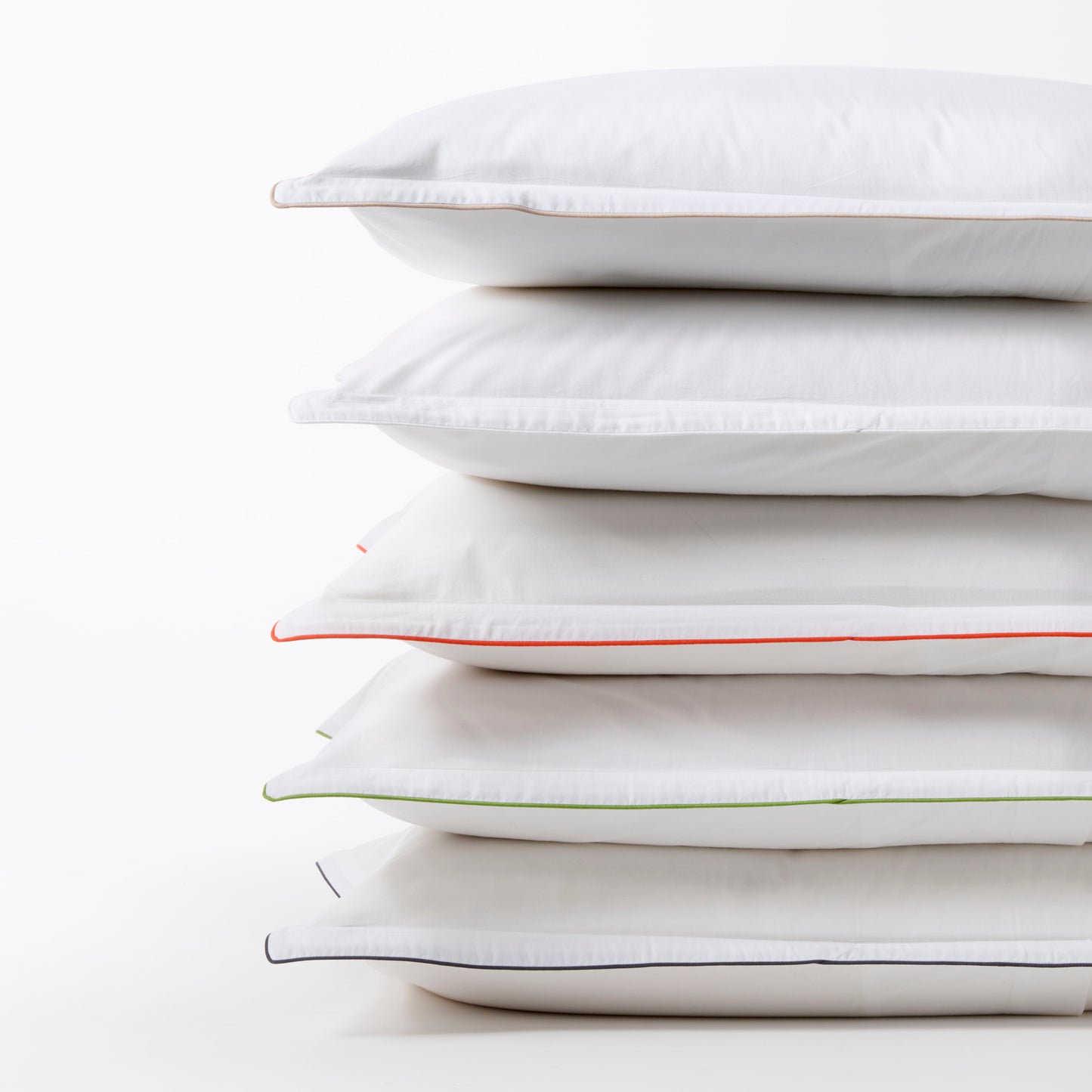 Stack of white percale duvet shams with navy, orange, green, and brown piping.