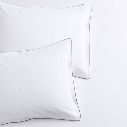 White percale pillow shams with navy piping and double-stitch detailing.