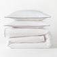 White percale duvet cover and two shams with navy piping, stacked neatly.