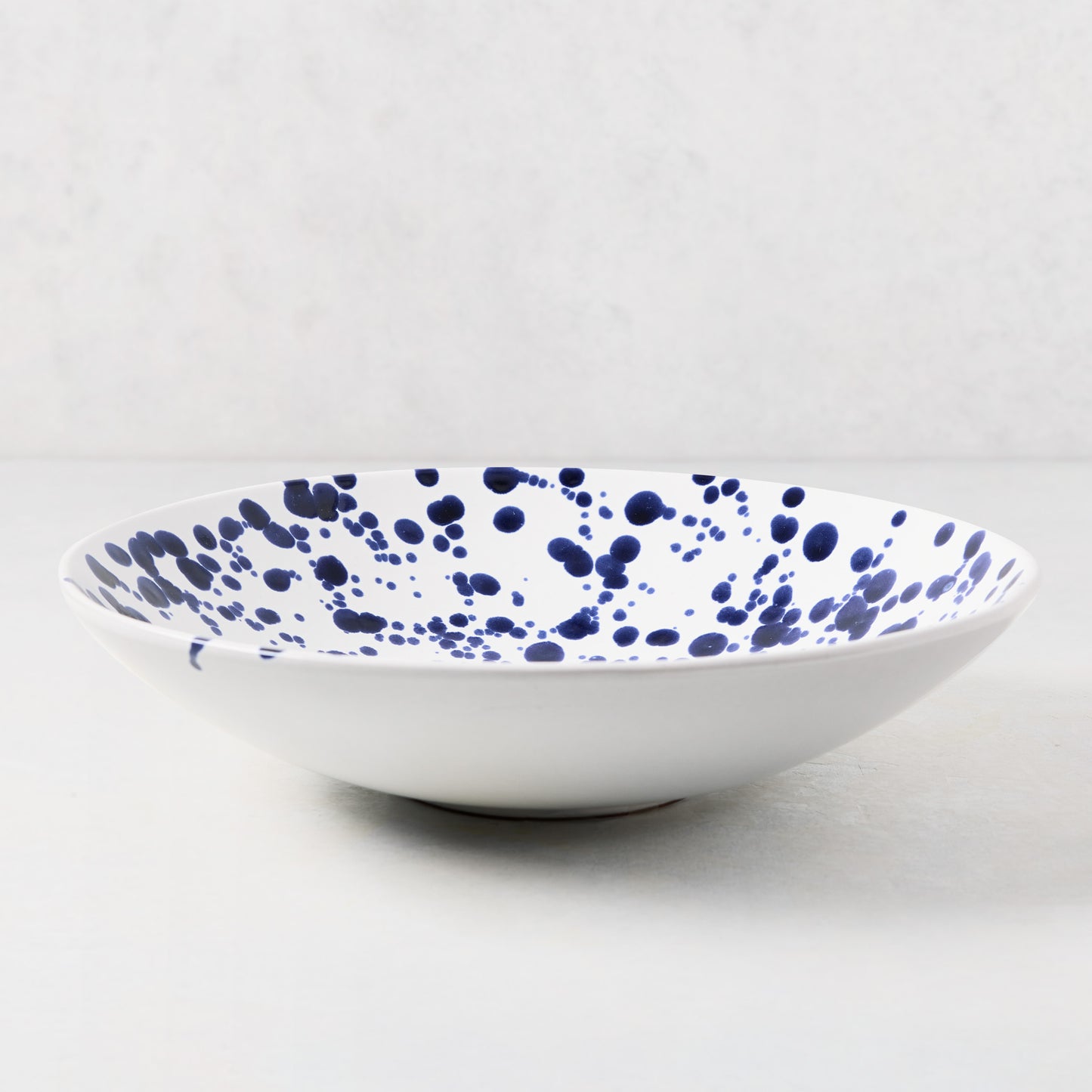 White stoneware serve bowl with navy blue hand-splattered pattern, 12"Dia x 3"H.