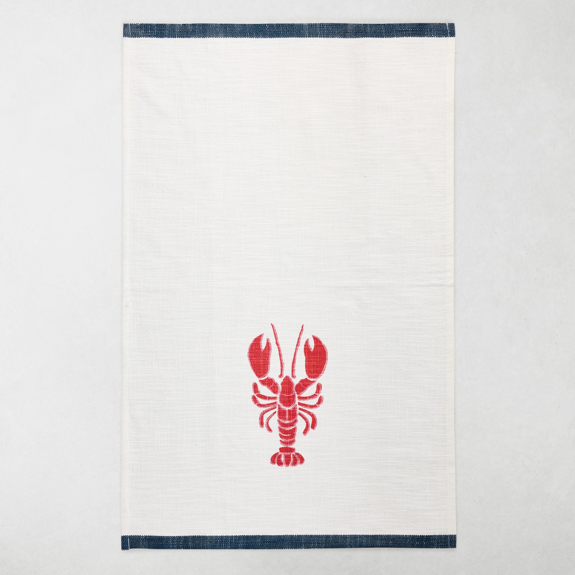 White cotton hand towel with a red lobster print and navy top and bottom borders.
