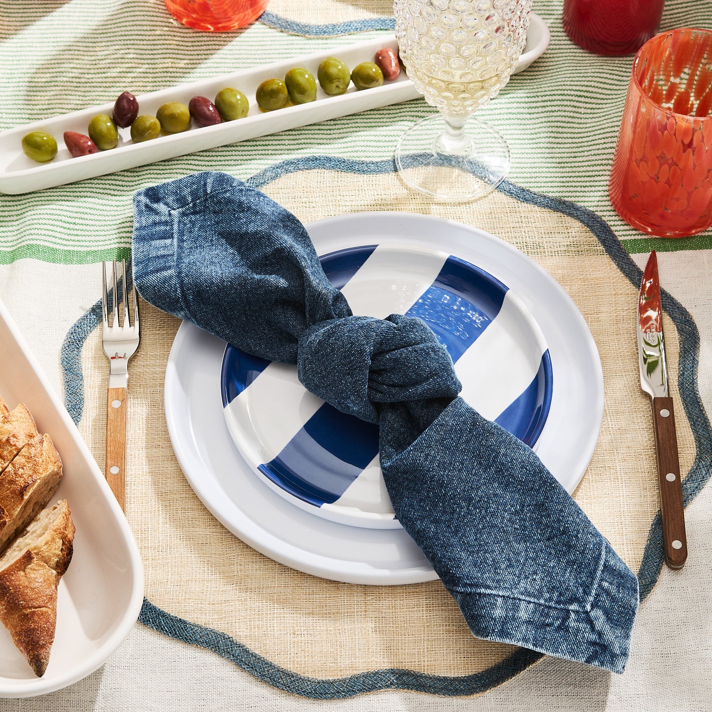 HG Navy Striped Melamine Salad Plate, 8"Dia, with a denim napkin on a woven placemat.