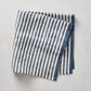 21-inch square cotton napkin with navy blue ticking stripes on a white base and a solid navy border.