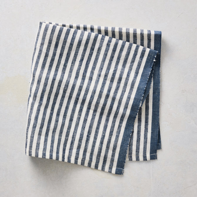 21-inch square cotton napkin with navy blue ticking stripes on a white base and a solid navy border.