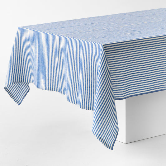Navy blue and white ticking stripe linen tablecloth with a contrasting border on a white table.