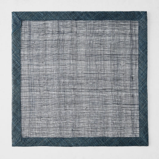 Navy blue square placemat made of woven abaca fibers with a semi-transparent center and solid border.