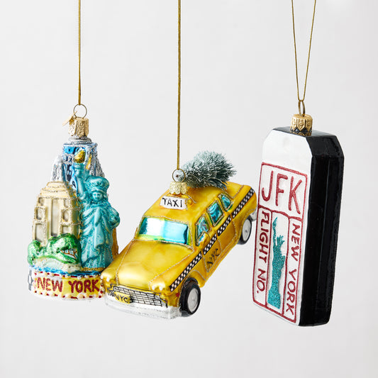 Hand-painted glass NYC Christmas ornaments featuring a skyline, yellow taxi, and JFK luggage tag with glitter accents.