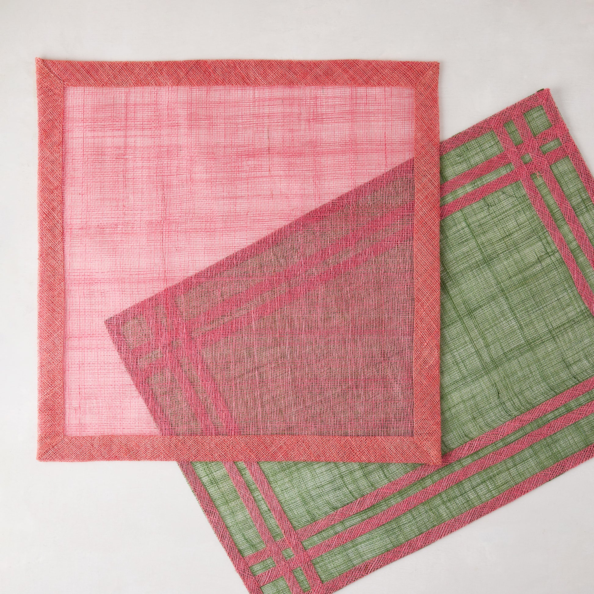 Newport Pink Square Abaca Placemat with dark pink border, partially overlapping a green placemat.