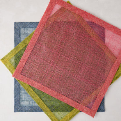 Newport Pink Square Abaca Placemat with dark pink border, layered over green and blue placemats.