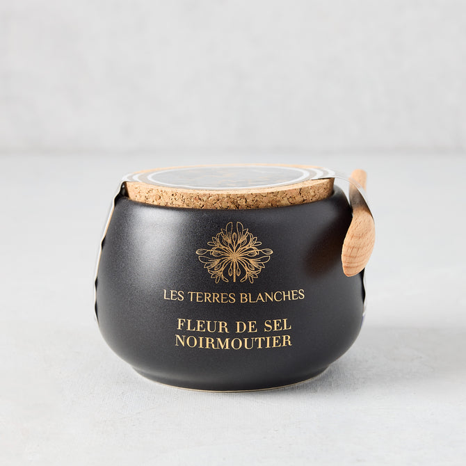 Black artisanal ceramic pot of Fleur De Sel salt with a natural cork lid and small wooden spoon.