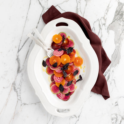 White Italian ceramic Nonna serving platter with handles, holding a colorful salad, on a marble surface.